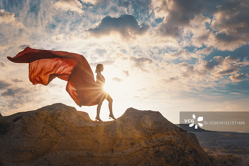 穿着长裙，衣服飞舞的女人，日出图片素材