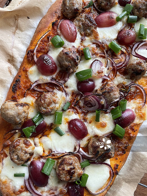 新鲜出炉的自制披萨，香肠、葡萄、马苏里拉奶酪、红洋葱和葱，丰富的番茄酱图片素材
