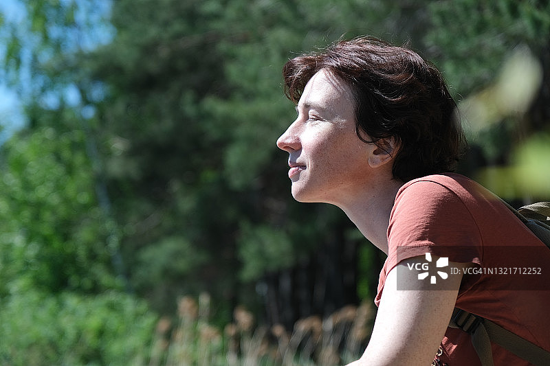 中年妇女坐在夏日湖畔，望着湖水图片素材