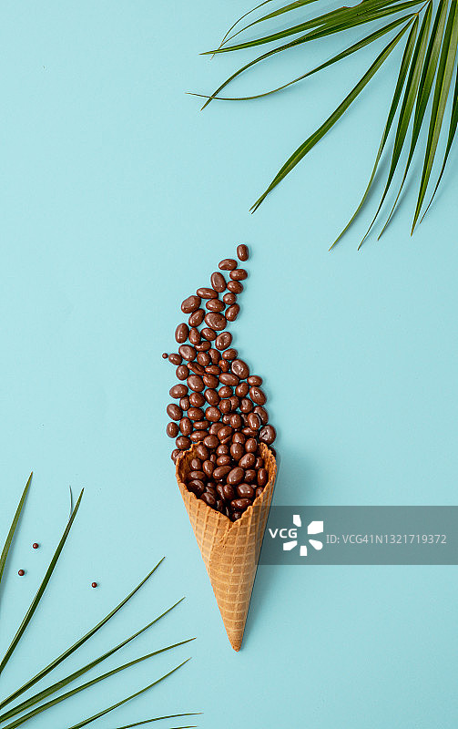 蓝色背景上的咖啡豆冰淇淋甜筒，简约概念图片素材