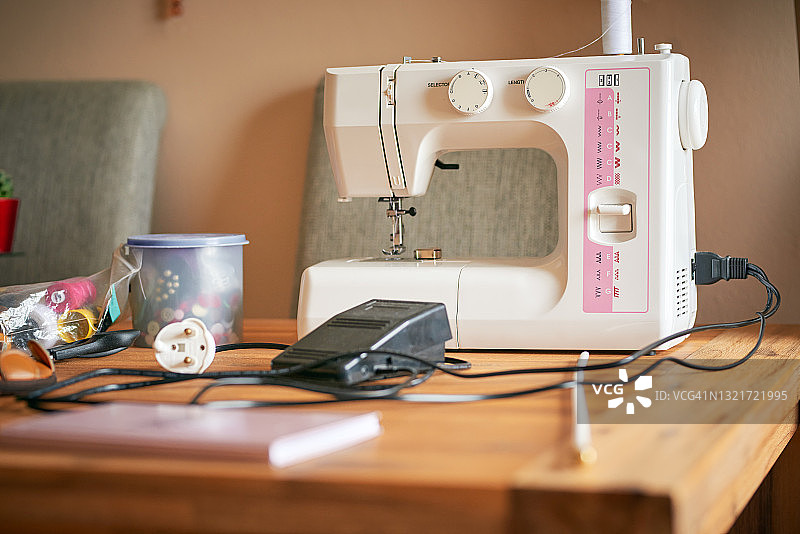 空荡荡的工作室里，桌子上放着一台缝纫机和其他缝纫用品图片素材