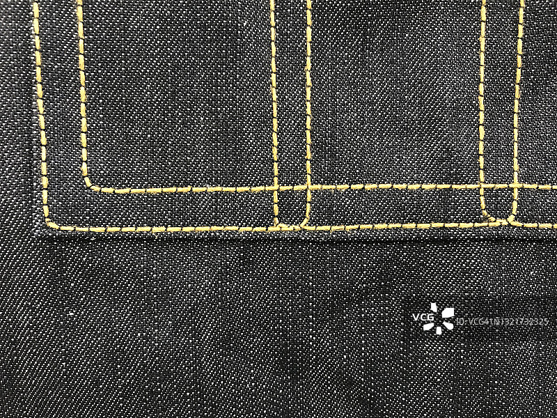 黑色牛仔布上的口袋，带黄色双缝线图片素材
