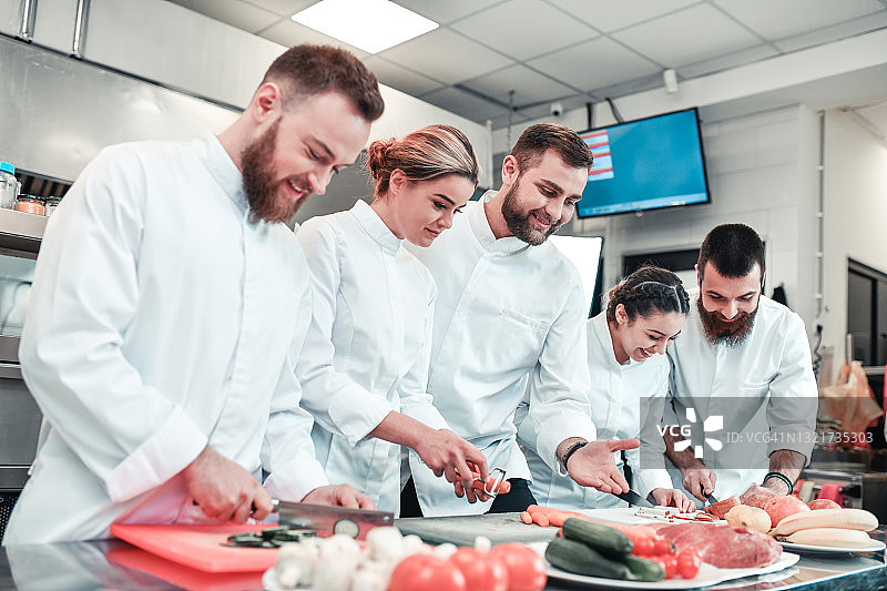 微笑的厨师在餐厅厨房一起烹饪学习图片素材