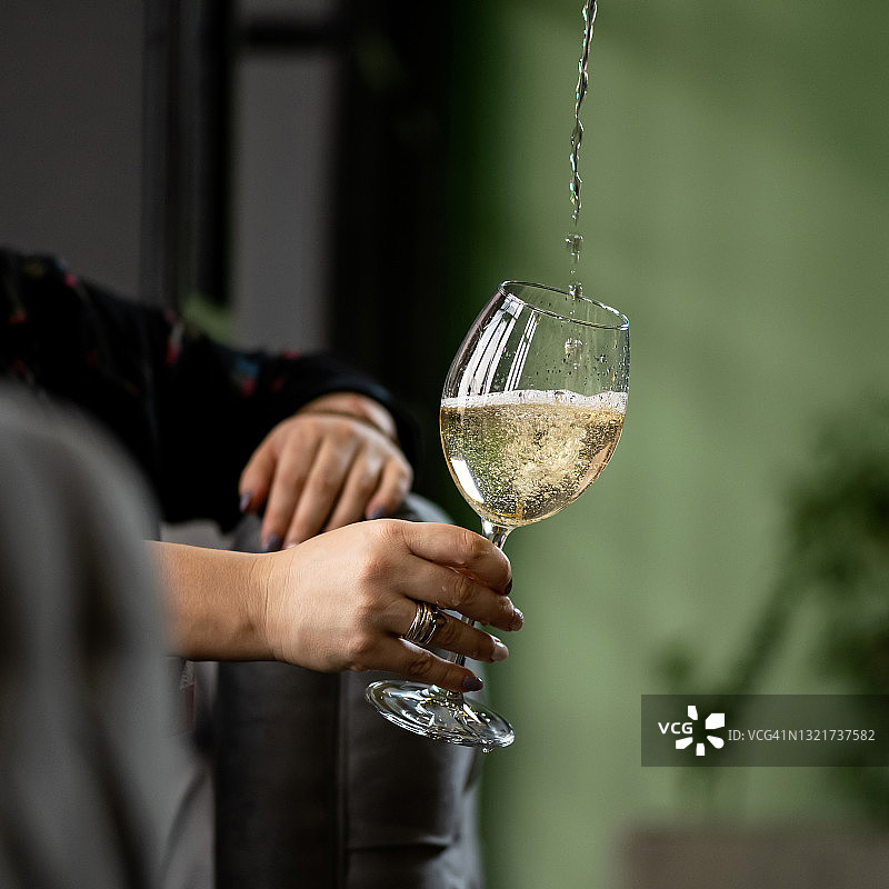女人将酒杯放在倾倒的白葡萄酒流下的图片。放松的女人概念。特写镜头图片素材