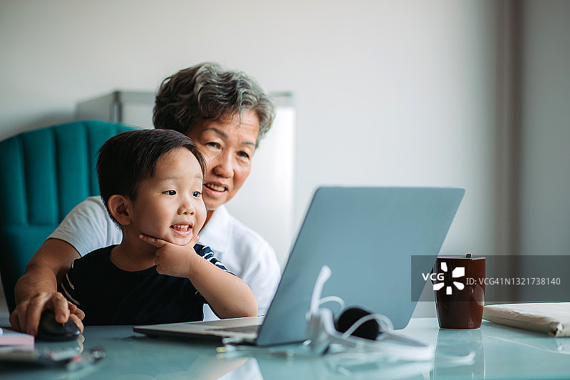 在办公室使用笔记本电脑的亚洲祖孙图片素材