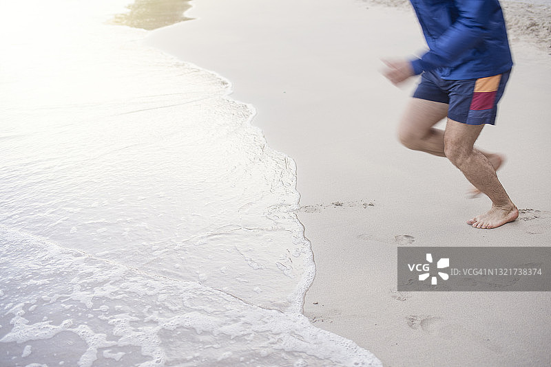 男子在海滩岸边跑步的低角度照片图片素材