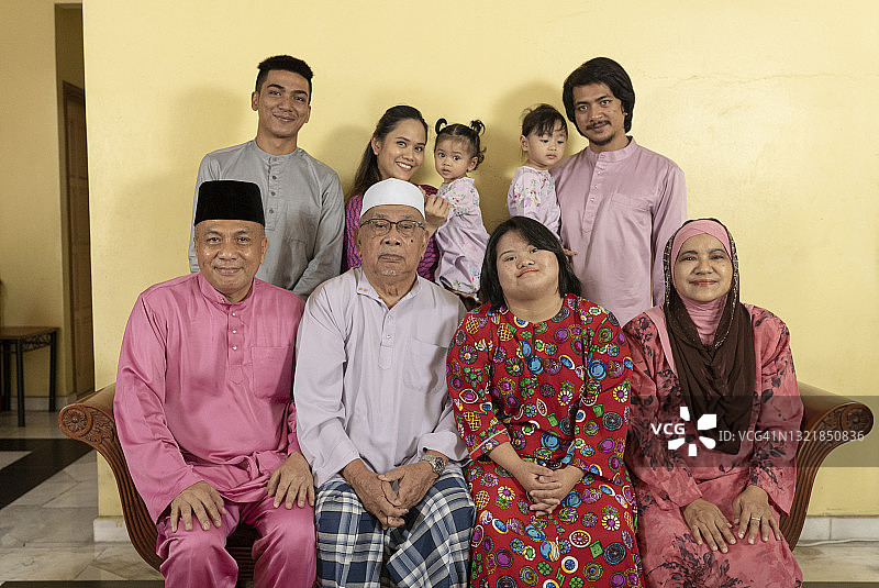 穿着传统服装的马来西亚亚洲家庭在家中合影，看着镜头微笑图片素材