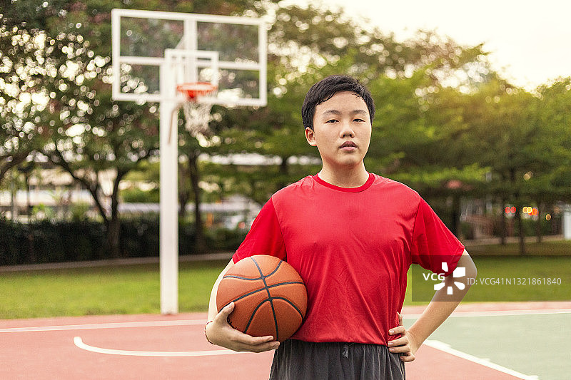 自信的年轻篮球运动员在球场上持球图片素材