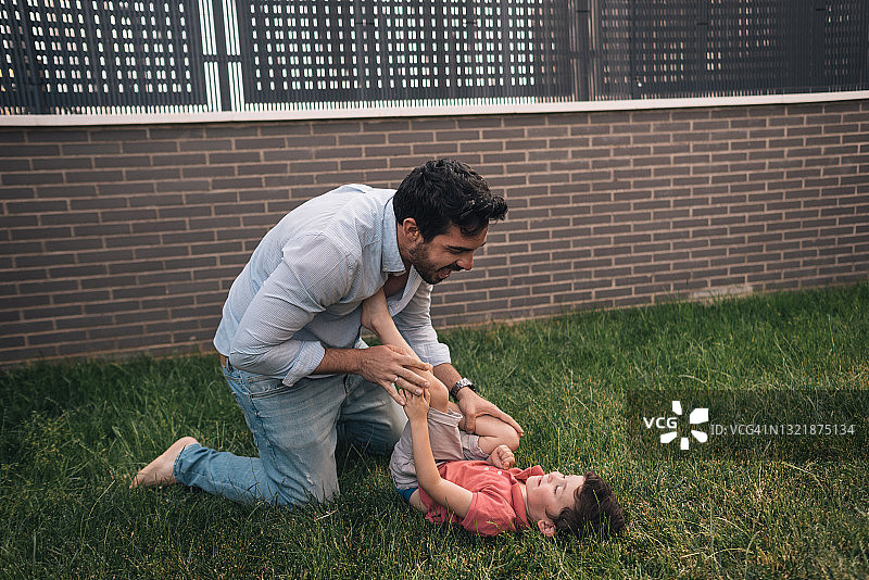 父亲在自家花园里和小儿子玩耍图片素材