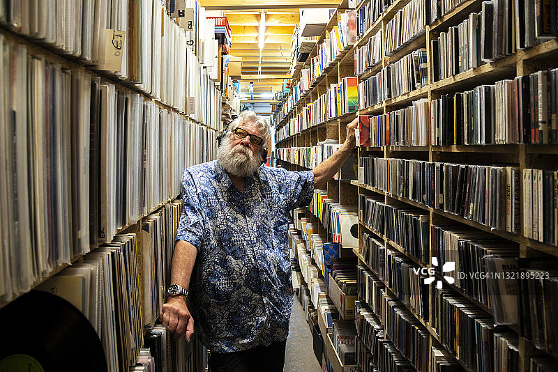 戴着耳机，在其收藏品前的唱片收藏家图片素材