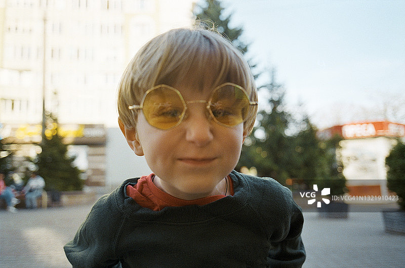 戴黄色太阳镜的五岁男孩城市肖像图片素材