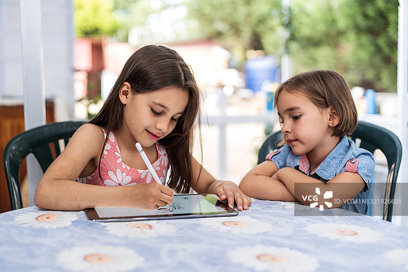 两个快乐的小女孩一起在户外用数位板绘画图片素材