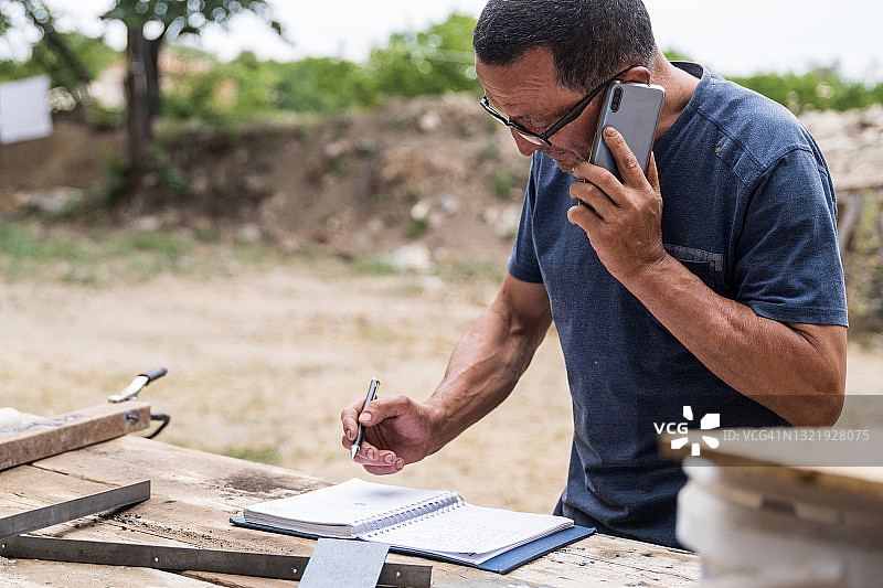 村民在工作台上阅读笔记并进行金融业务通话图片素材