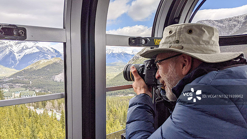 男人在缆车上拍摄落基山脉图片素材