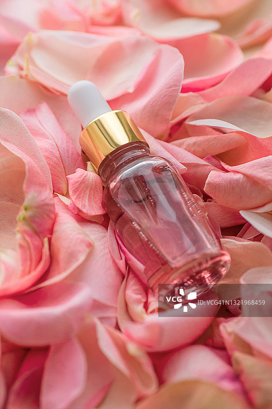 玫瑰花瓣中的一小瓶粉色美容油图片素材