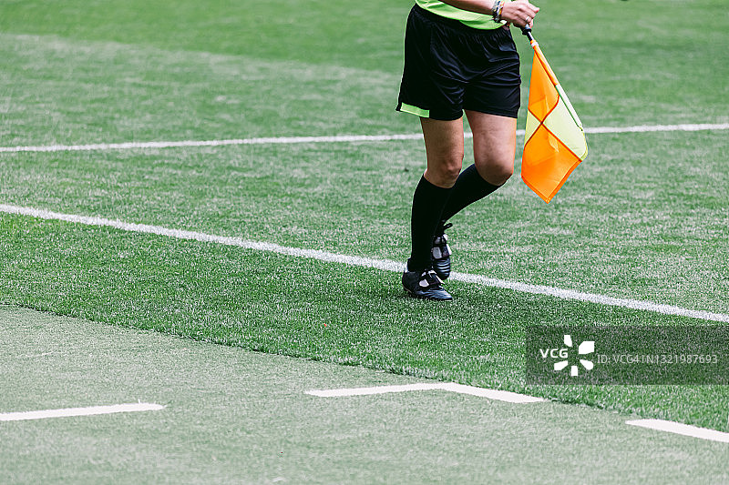 足球助理边裁女裁判带着旗子在场上比赛，移动着。图片素材