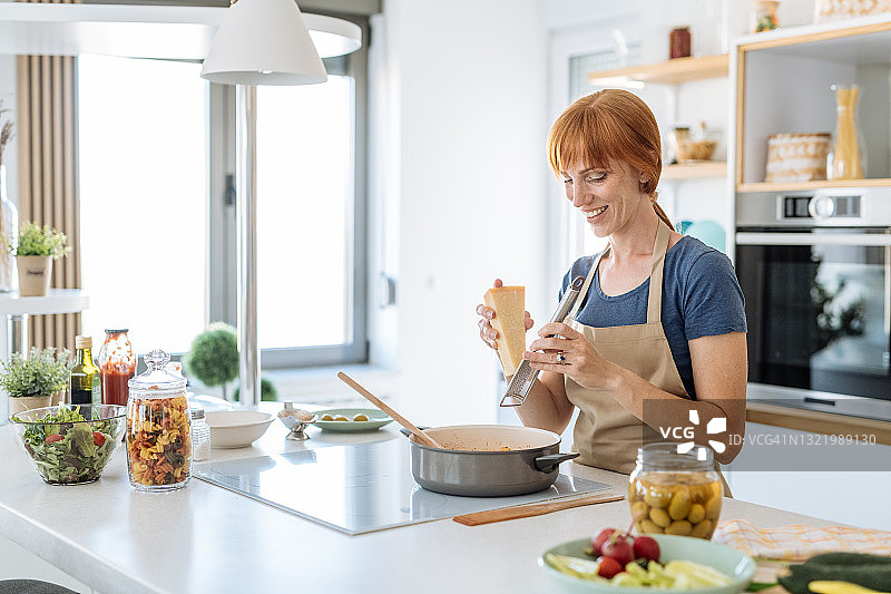 红发中年女人穿围裙烹饪地中海美食图片素材