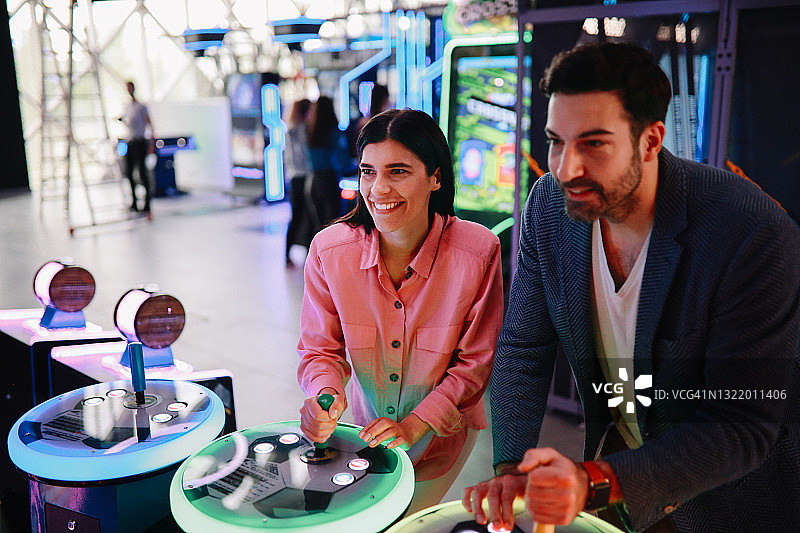 在游戏厅玩团队模式的年轻情侣图片素材