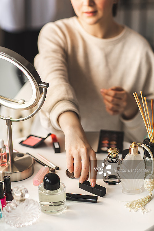 女人的手伸出去从摆满美容产品的桌子上拿起口红图片素材