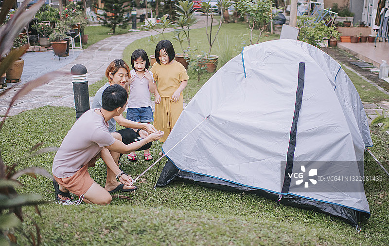 中国亚洲父亲在后院搭建露营帐篷图片素材