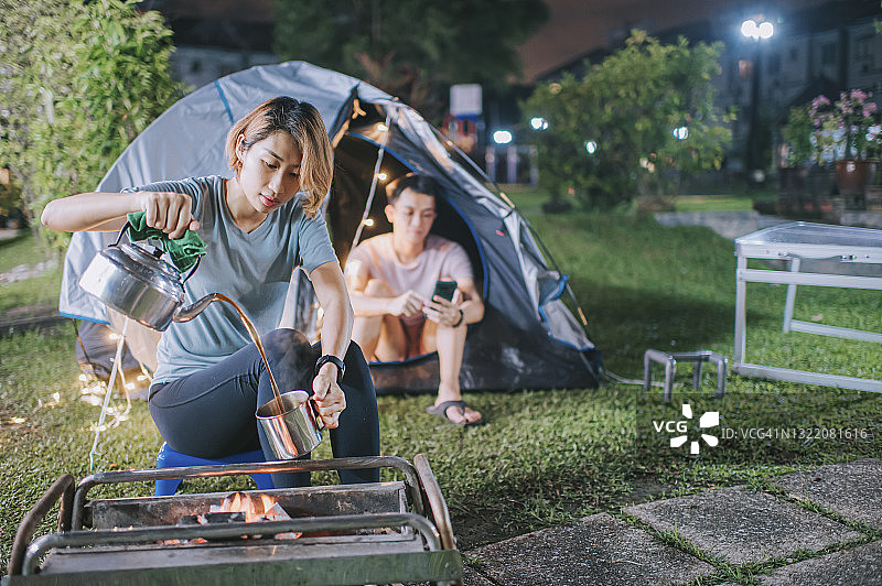 亚裔华人夫妇在自家后院露营帐篷里放松休息，享受周末居家活动图片素材