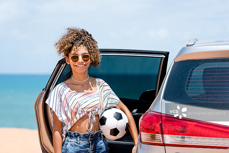 在海滩附近，拿着足球，看着镜头的微笑少女图片素材