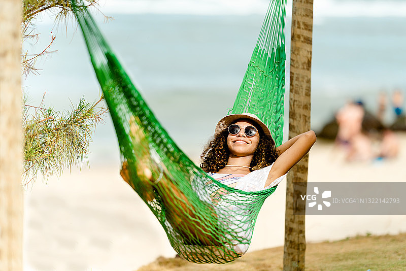 年轻女人在海滩的吊床上放松图片素材