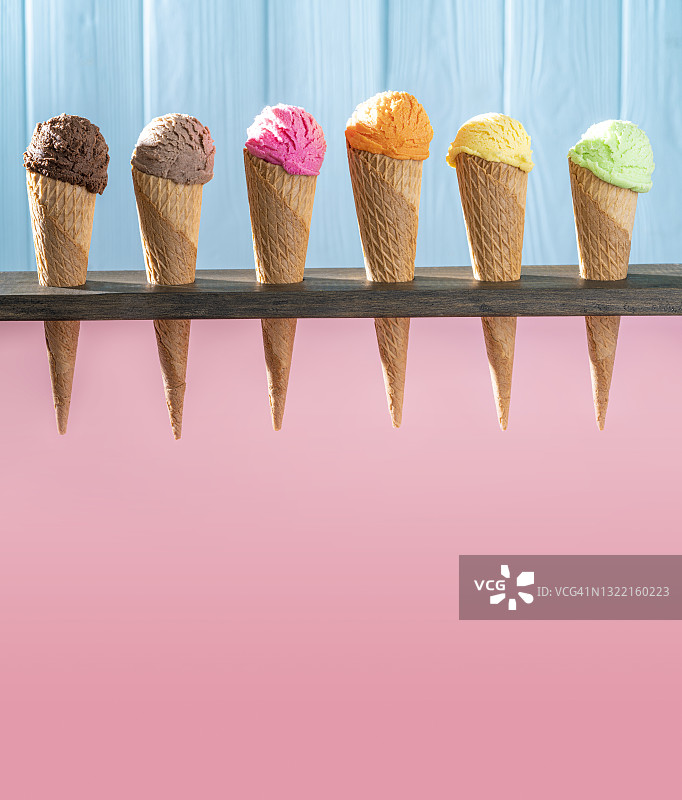 一排什锦冰淇淋蛋卷，粉色和蓝色木纹背景图片素材