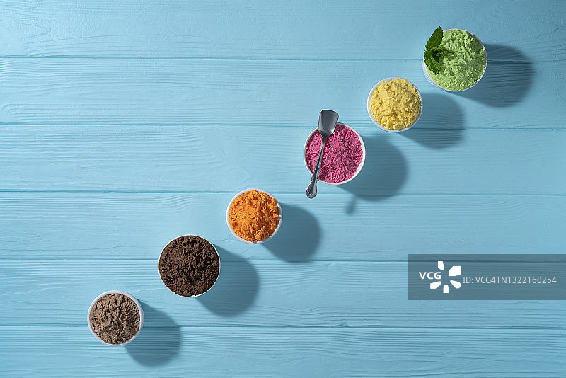 蓝色木纹背景上的什锦冰淇淋杯和华夫饼甜筒图片素材