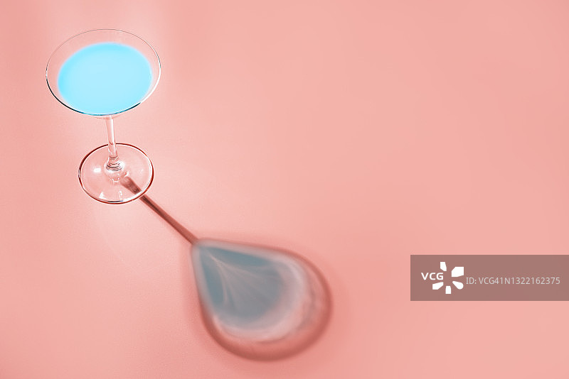 粉色背景下带有硬光和阴影的蓝色无酒精鸡尾酒图片素材