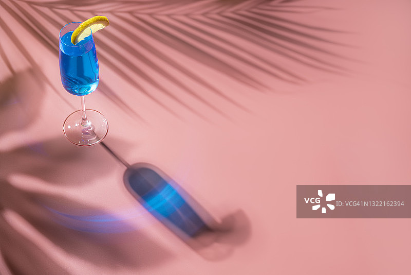 粉色背景下带有硬光和阴影的蓝色无酒精鸡尾酒图片素材