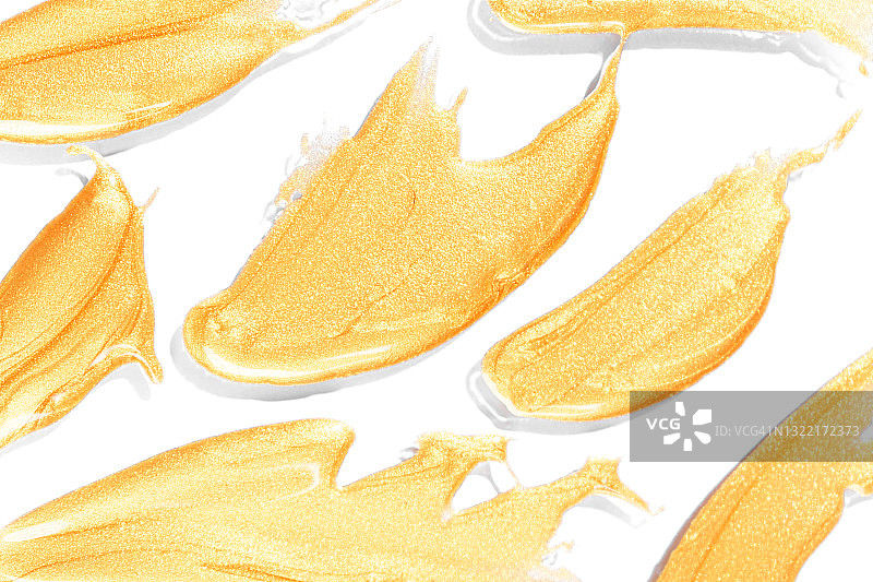 白色背景上的金色油漆笔触和指甲油化妆品图片素材