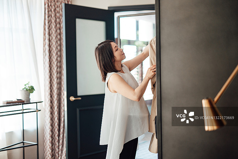 年轻女子从衣柜里挑选服装，准备外出图片素材