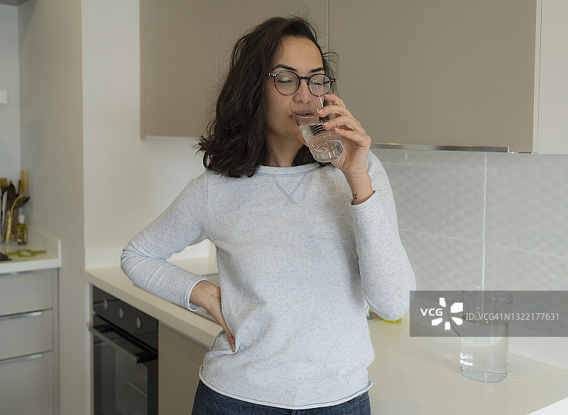 年轻女人在厨房喝水图片素材