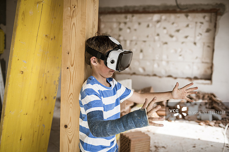 戴着VR头显，在阁楼装修时伸手的男孩图片素材