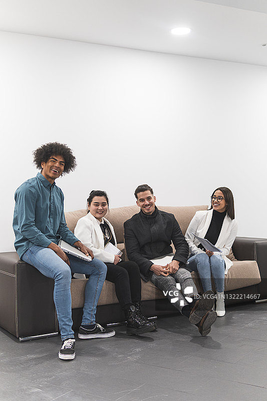 在办公室沙发上就座的快乐男女职业人士图片素材