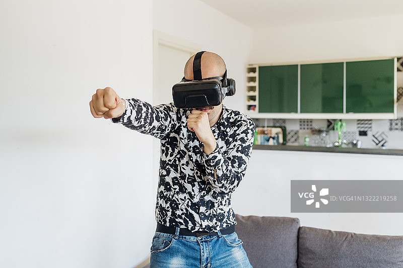 在家中戴着VR模拟器进行拳击的年轻男人图片素材