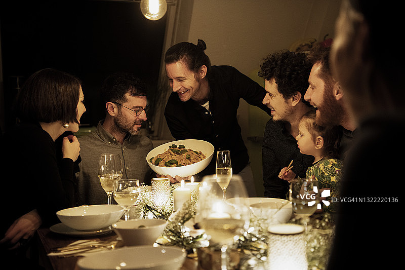 微笑的男士和女士看着厨房里拿着意大利面的中年男人图片素材