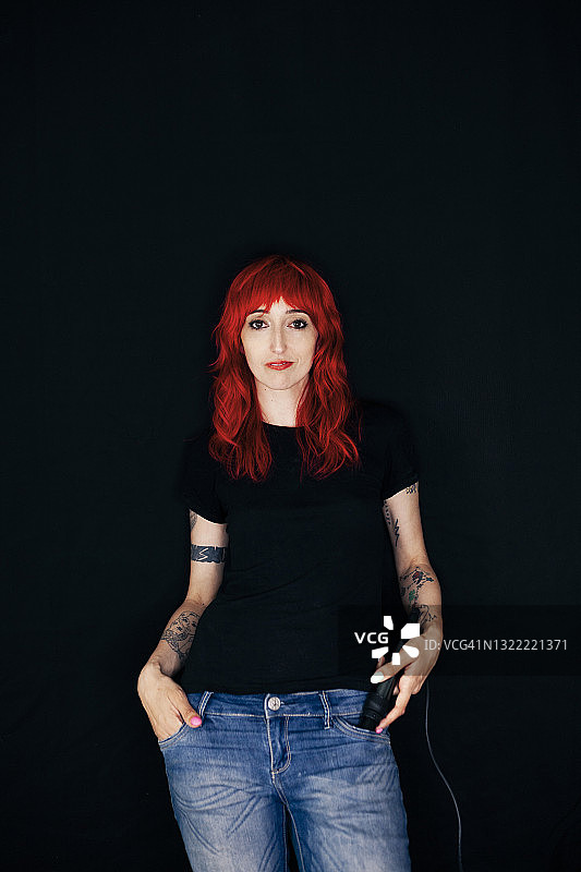 站在黑色背景上手插口袋的美丽女发型师图片素材