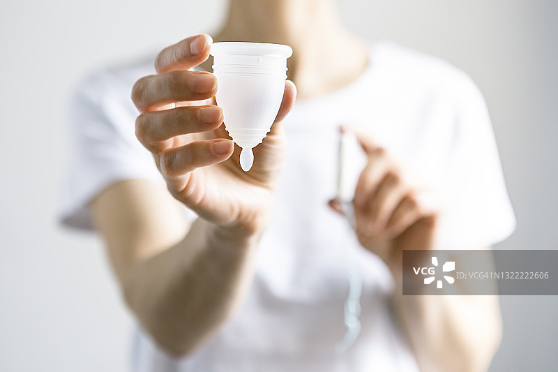 女人手持月经杯，白色背景图片素材