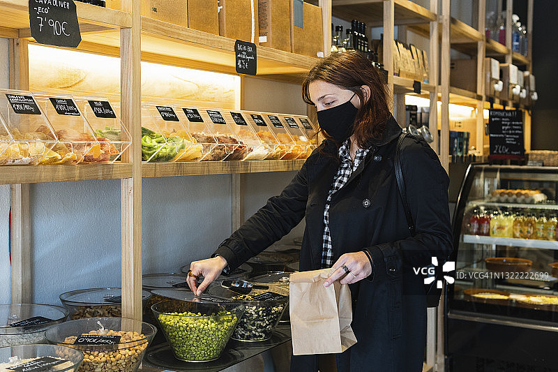 疫情期间，戴防护口罩的女人在超市购买青豌豆图片素材