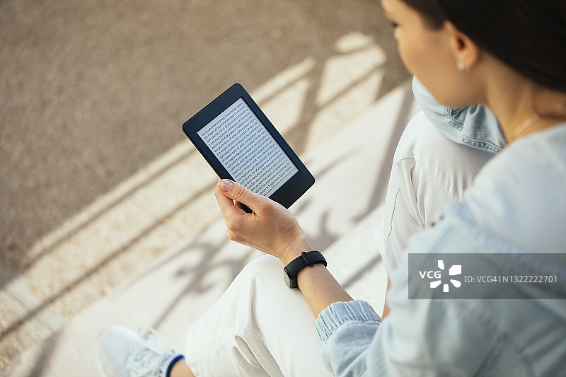 坐在台阶上看电子书的女人图片素材