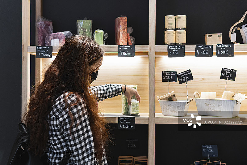 戴防护口罩的女人在商店里挑选食物图片素材