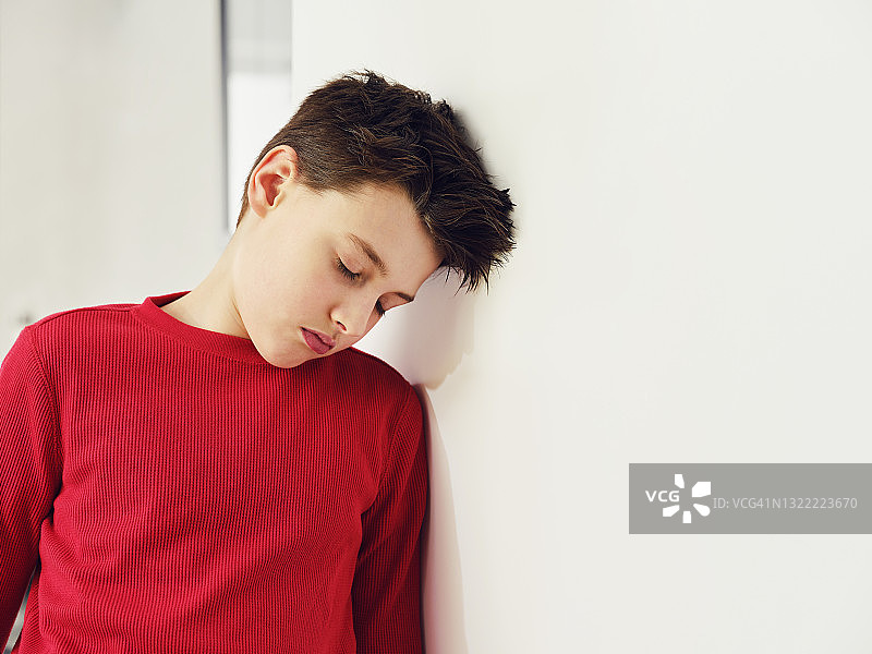 疲惫的男孩闭着眼睛靠在墙上图片素材