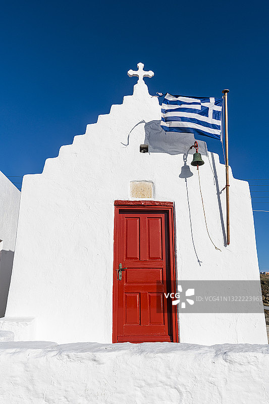 希腊米科诺斯岛上的粉刷教堂与希腊国旗图片素材