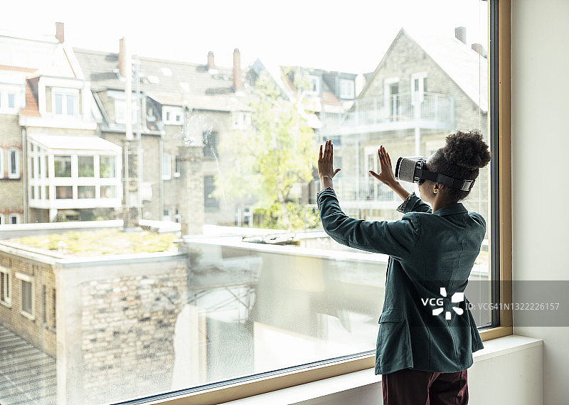 在办公室使用VR头显触摸玻璃窗的职业女性图片素材