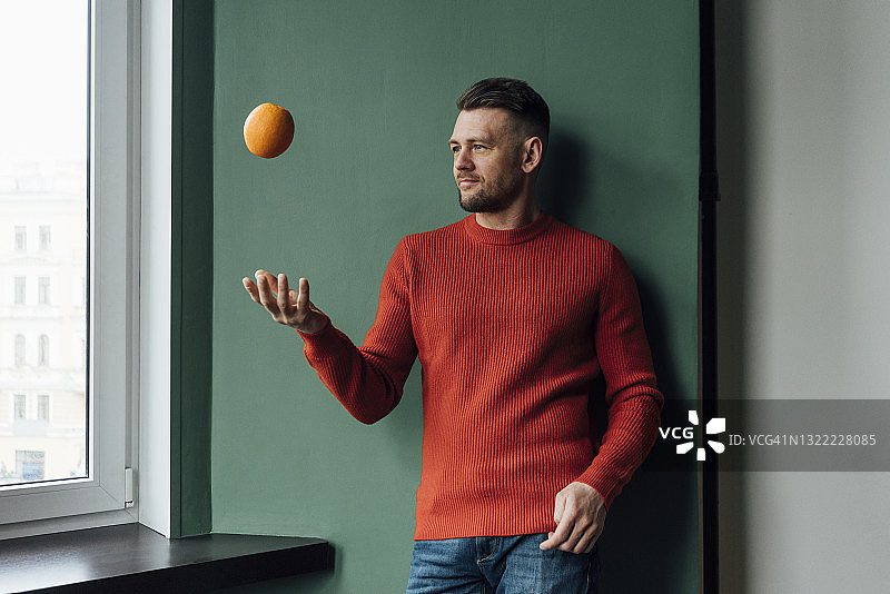 男商人在墙前玩橙子图片素材