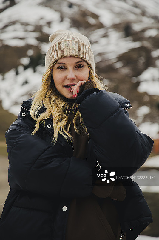 在雪山前戴针织帽的金发女人图片素材