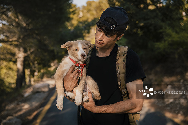 在森林里背着背包和宠物站立的年轻男人图片素材