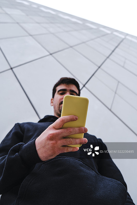 男子靠墙使用智能手机图片素材